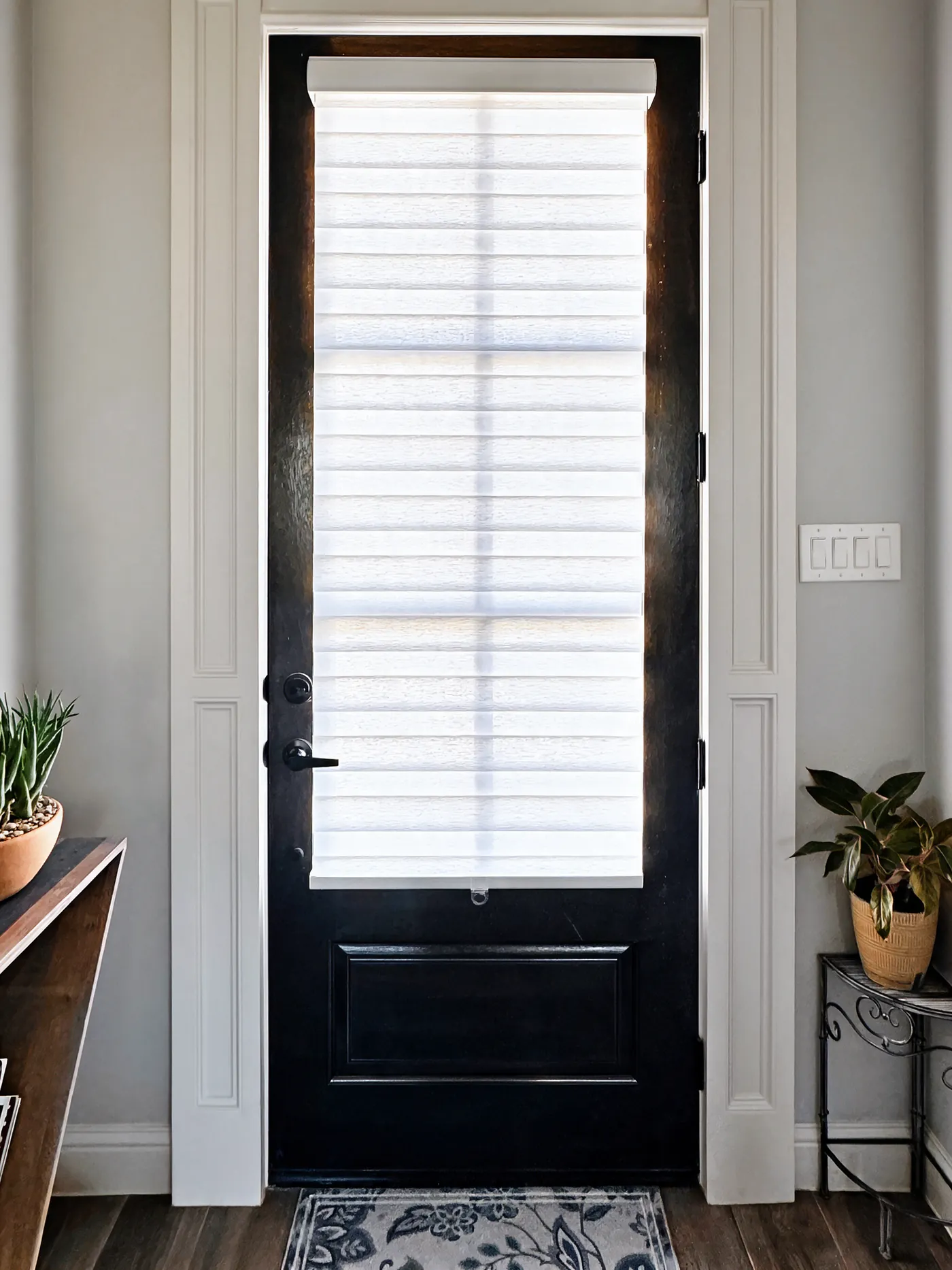 White zebra shade on the glass of a black front door