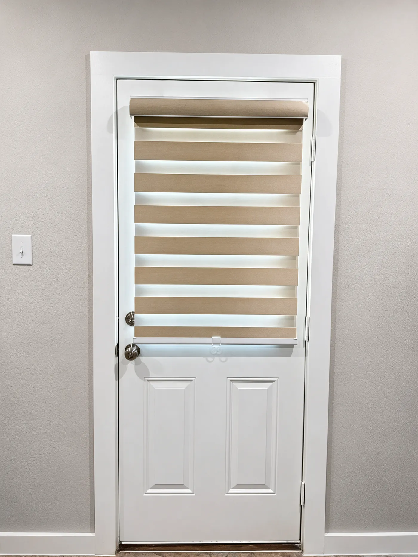 Beige zebra shade on the window of a white back door