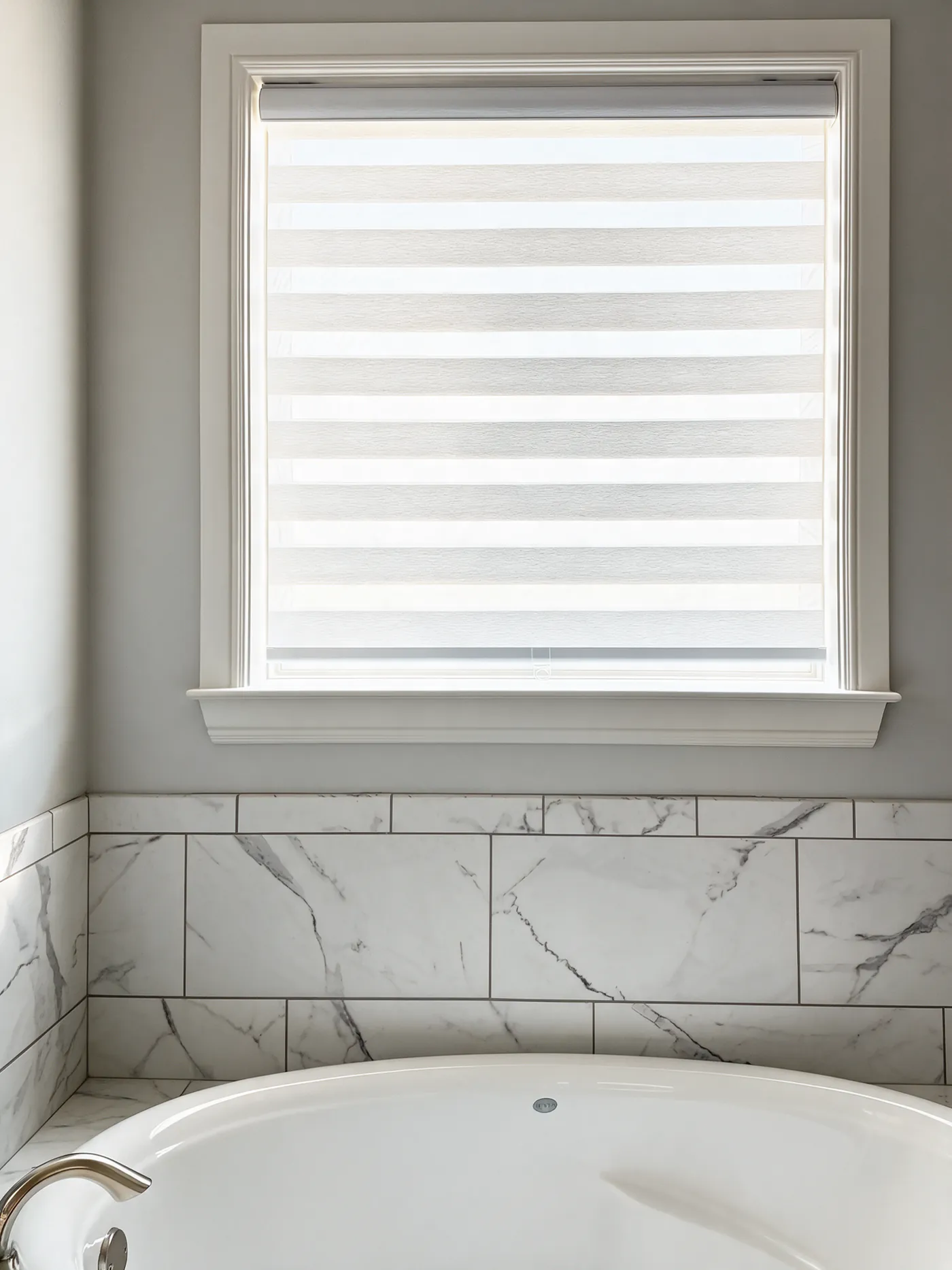 White zebra shade on a bathroom window above a soaking tub