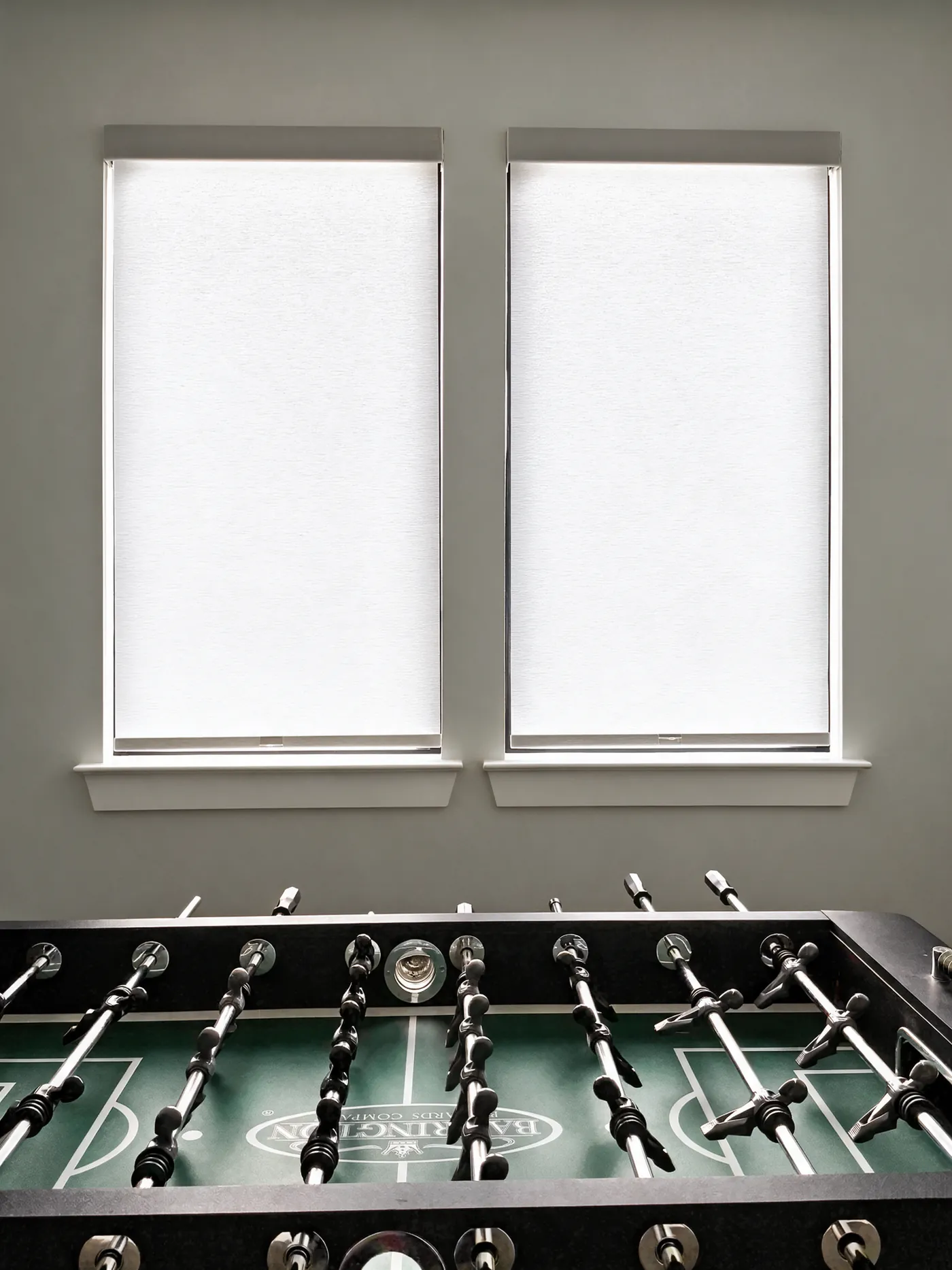 White roller shades on two windows in a game room