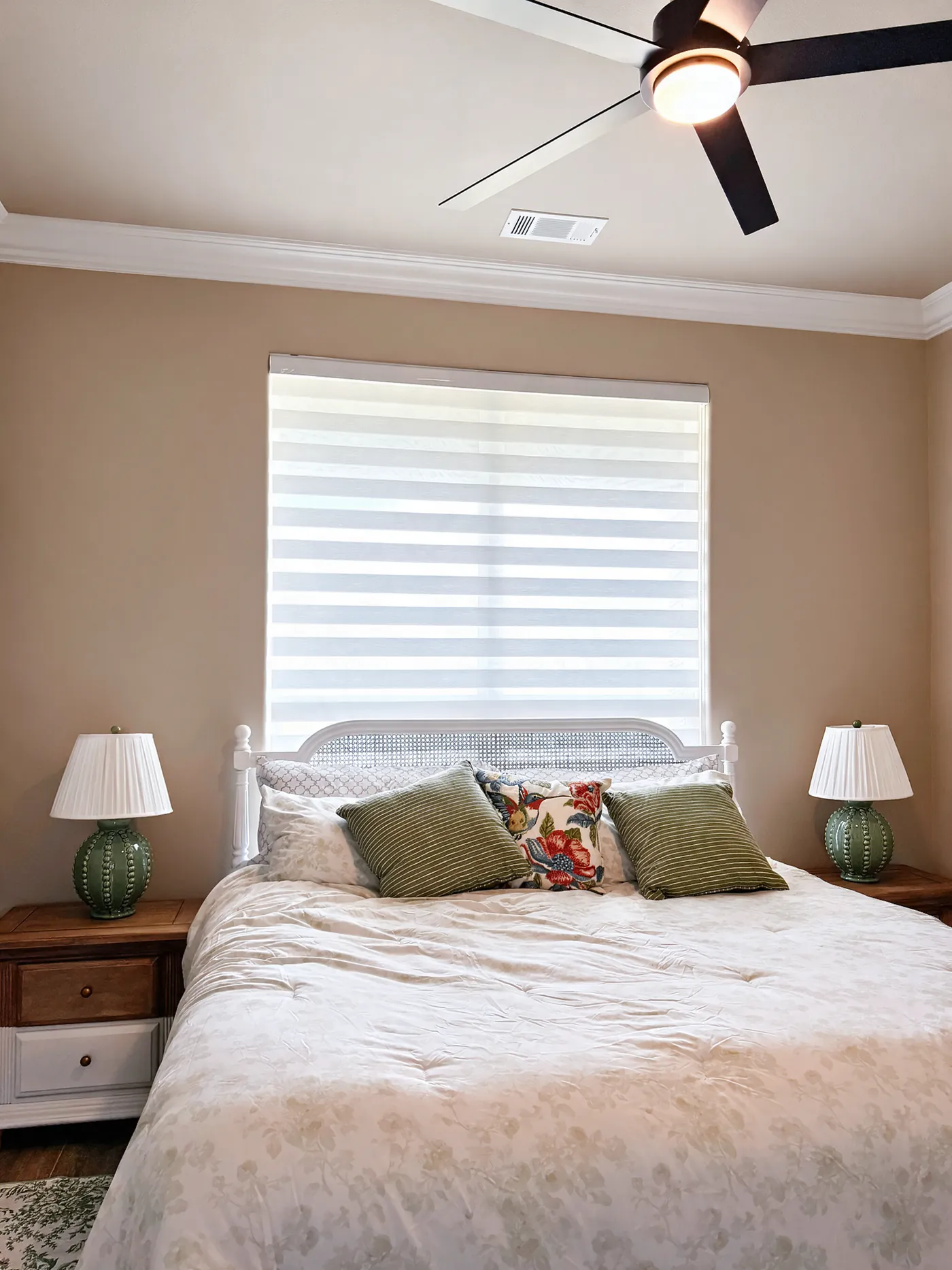 White zebra shade on the window behind a bed in a primary bedroom
